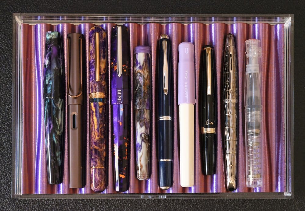 Acrylic drawer with a duotoned, 3D-printed tray holding 10 different fountain pens of varying shapes, sizes, and colors