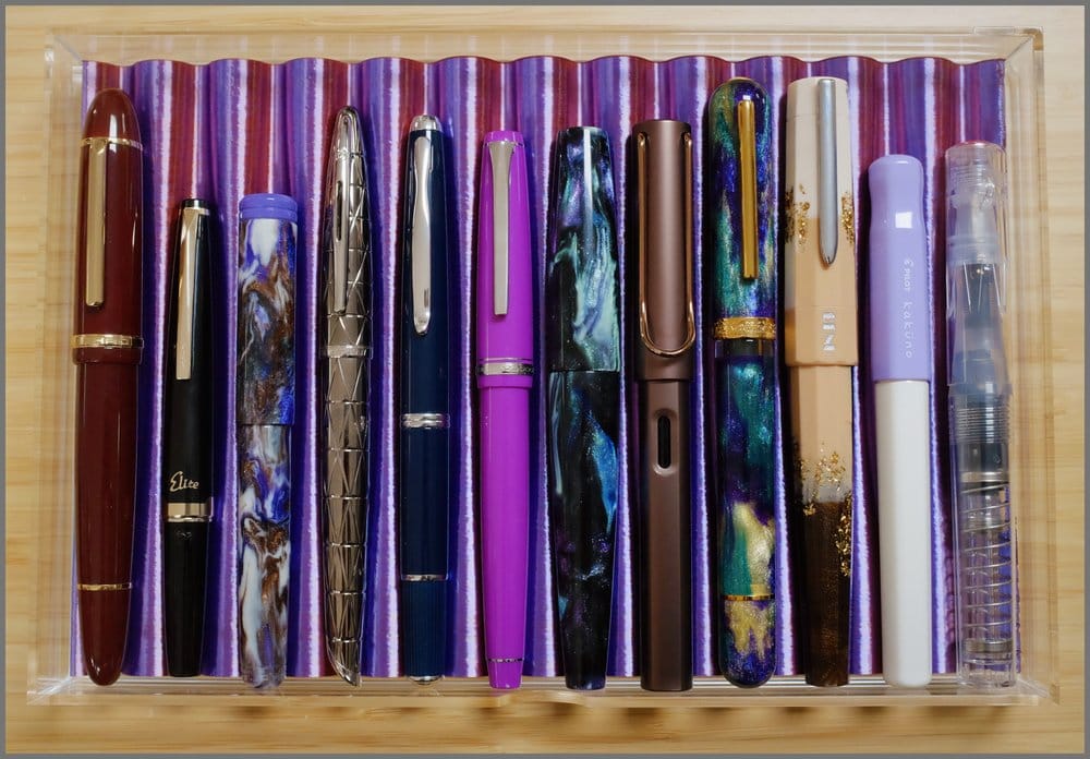 Acrylic drawer with a duotoned 3D-printed tray holding 12 different fountain pens of various colors and shapes