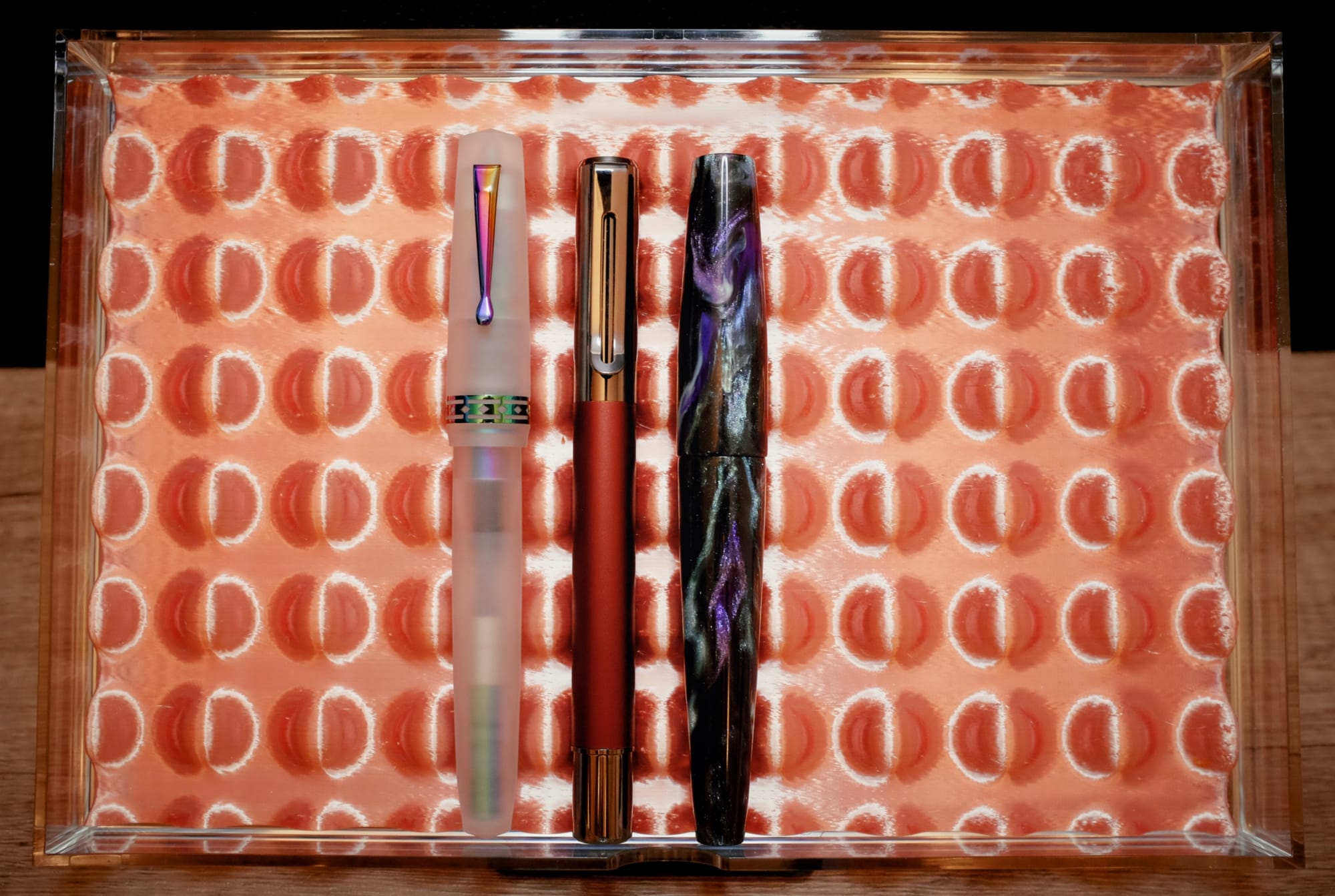 An acrylic drawer with a copper-colored 3D-printed tray holding 3 various fountain pens of different designs and sizes