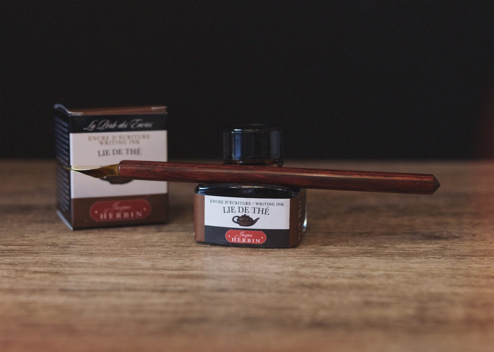Bottle of Lie de Thé with a folded nib pen on the built-in pen rest at the front of the bottle, a distinctive feature of this line of inks.