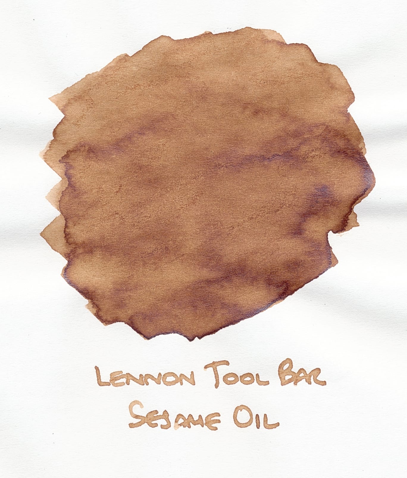 Swatch of a medium light brown ink with visible shading in areas where more of the ink pooled around the edges, a label of "Lennon Tool Bar Sesame Oil" written underneath