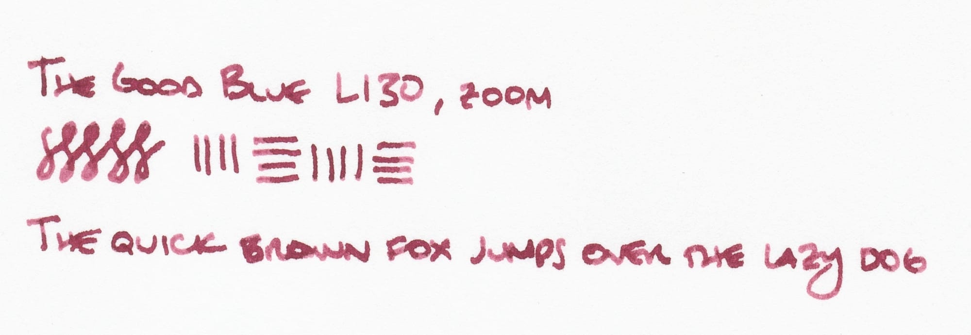 Writing sample in a purpley, wine red ink: "The Good Blue L130, zoom", figure-8 doodle, horizontal and vertical lines to show the line variation of the nib, and "The quick brown fox jumps over the lazy dog"