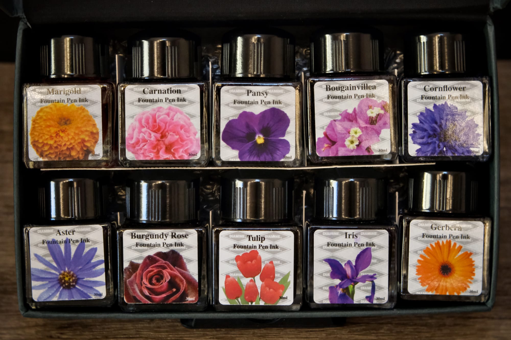 10 bottles of fountain pen ink with pictures of flowers that are the same color of the ink inside