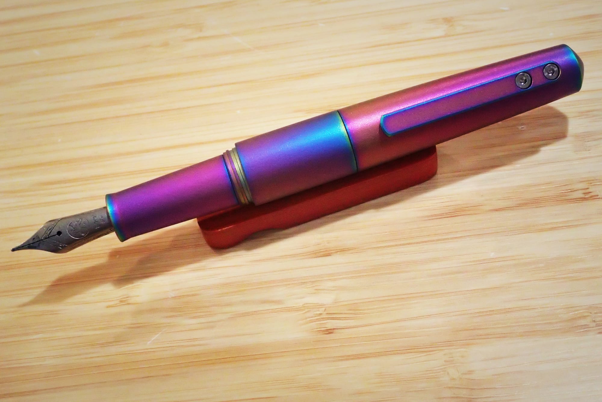 Rainbow titanium pocket fountain pen, cap posted on back to show length when writing