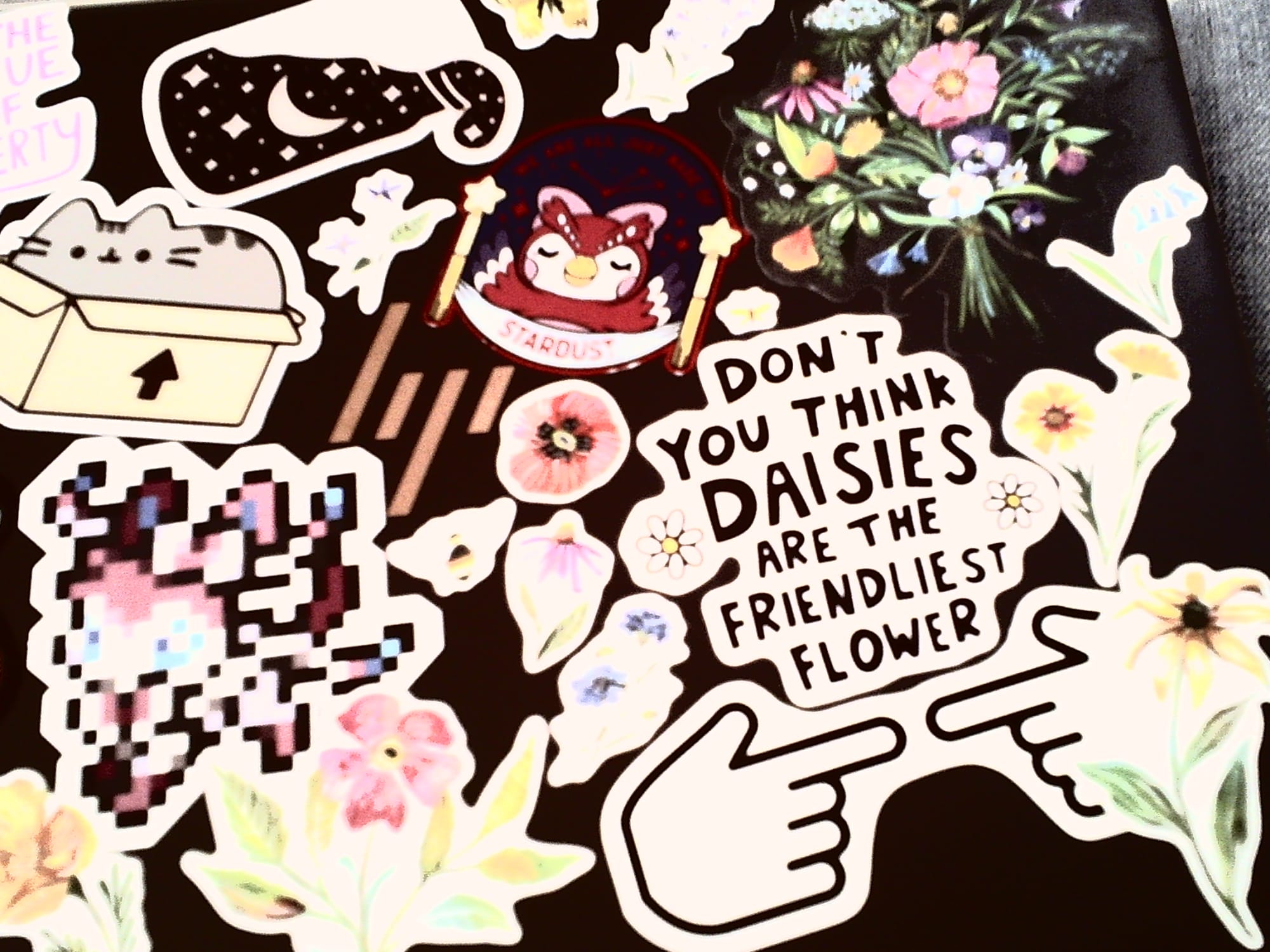 Overexposed color image of an HP laptop lid filled with various stickers of flowers, Pusheen, Celeste from Animal Crossing, etc.