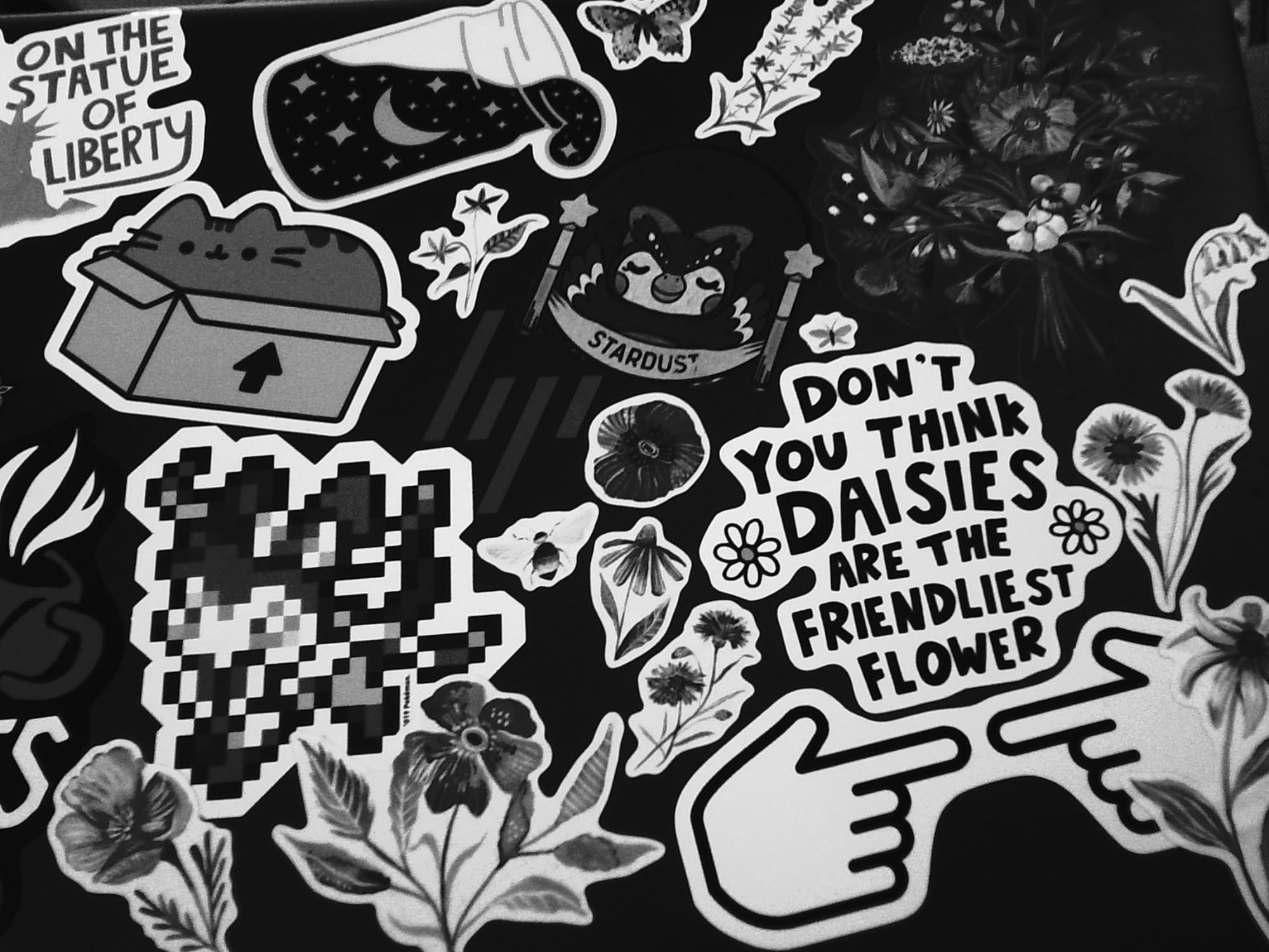 High contrast monochrome image of an HP laptop lid filled with various stickers of flowers, Pusheen, Celeste from Animal Crossing, etc.