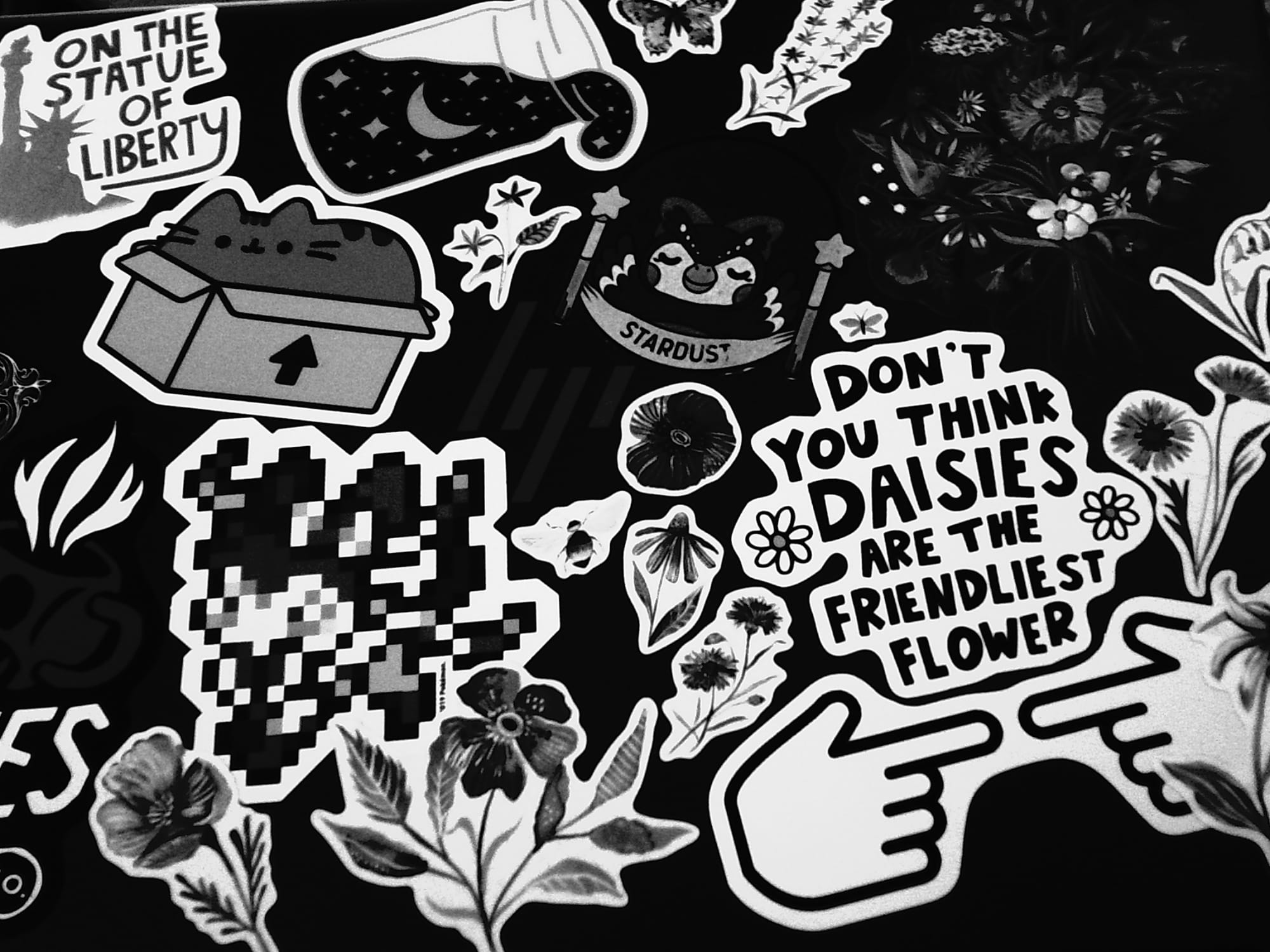 Even higher contrast monochrome image of an HP laptop lid filled with various stickers of flowers, Pusheen, Celeste from Animal Crossing, etc.