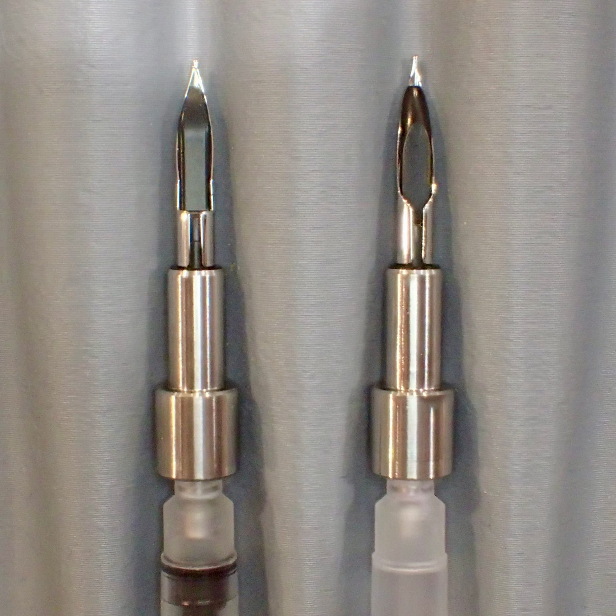 Close-up view of the underside of two nib assemblies showing the different shape of the feeds between them