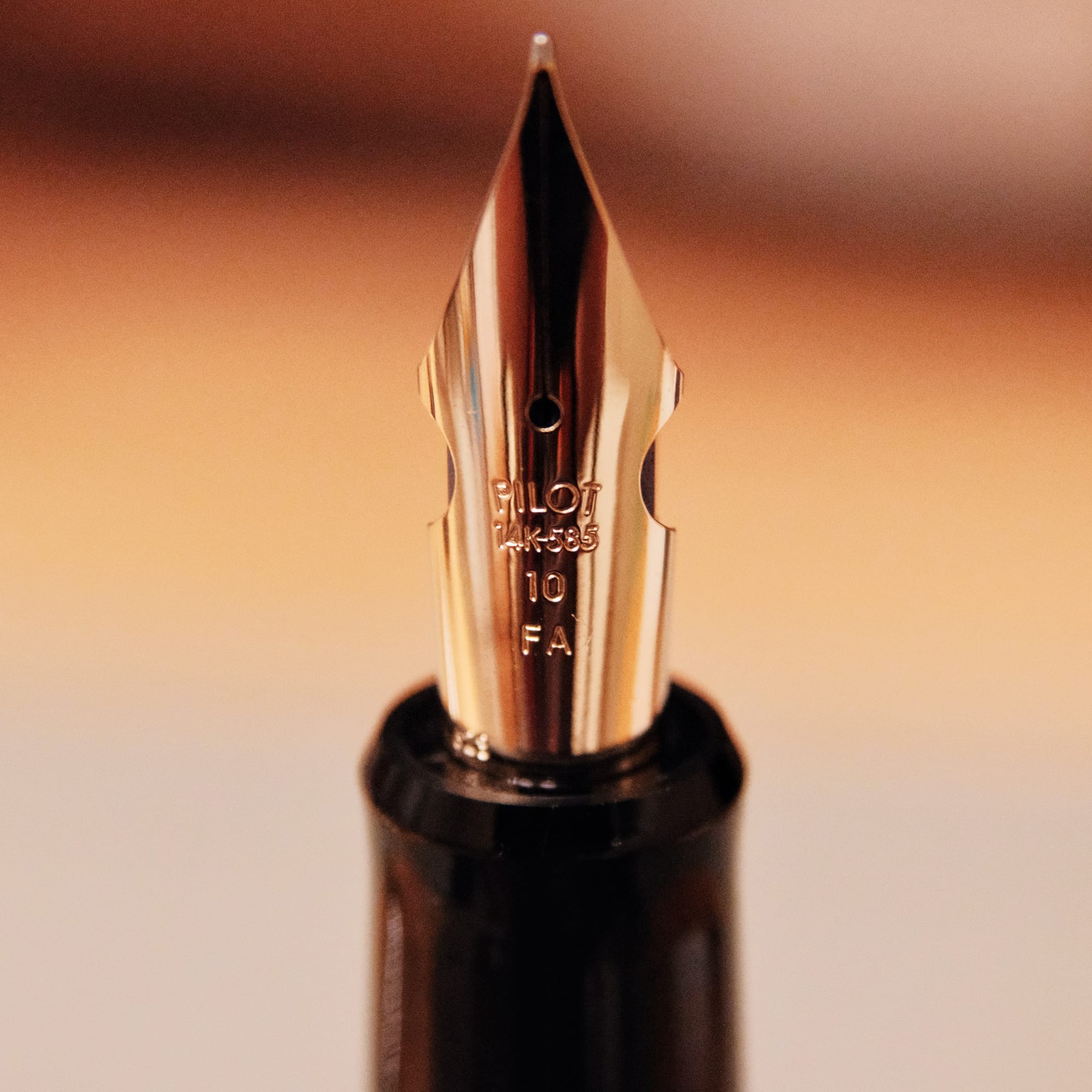 Very close up shot of a gold fountain pen nib with side cutouts, engraved "Pilot 14K-585 10 FA"