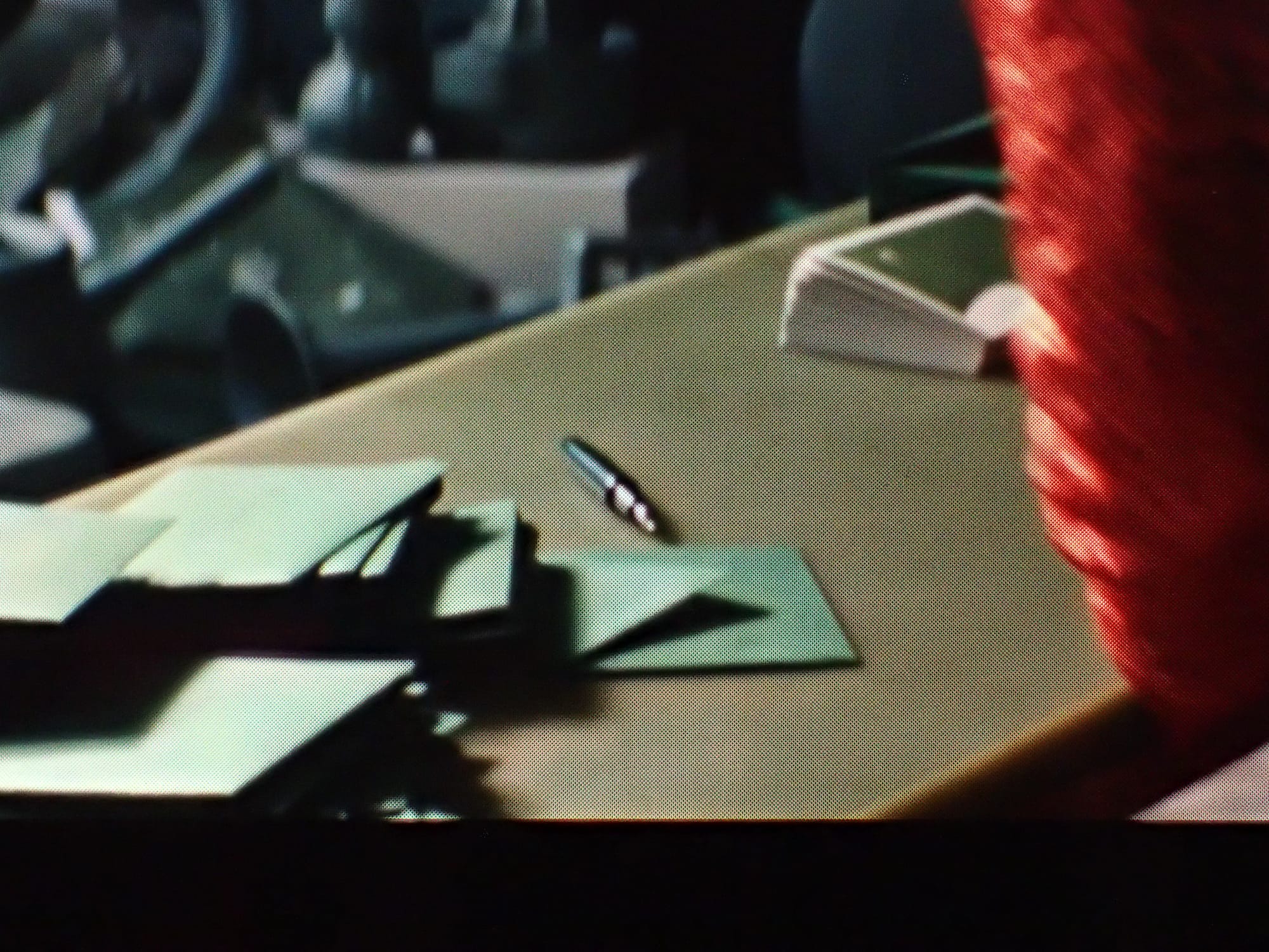 Wide view of a table with a stack of completed thank you cards in green envelopes, the uncapped green fountain pen, and a peek of a red sleeve on the right of the frame