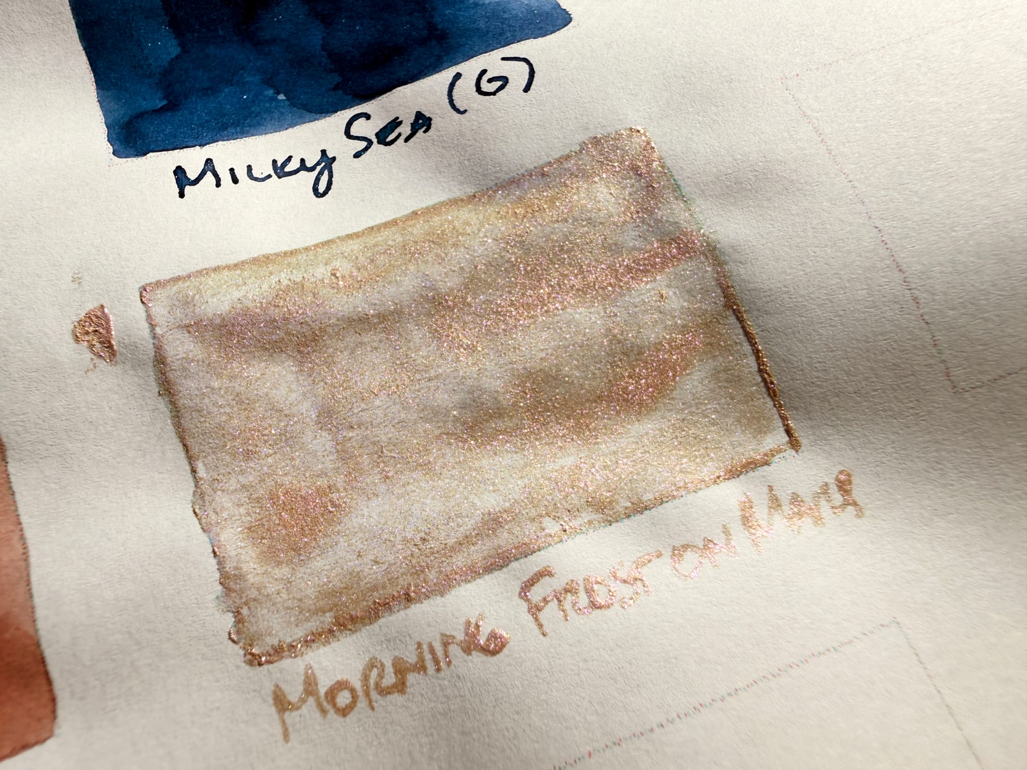 Close up on an ink swatch on paper, showing champagne colored shimmer clumping randomly everywhere