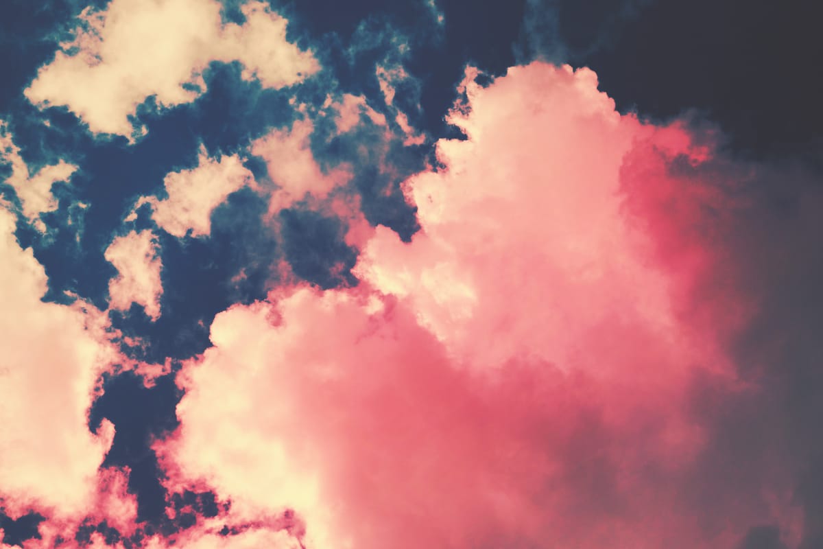 Pinkish poofy clouds in a dark blue sky artistically edited to enhance the dramatic appearance of the clouds