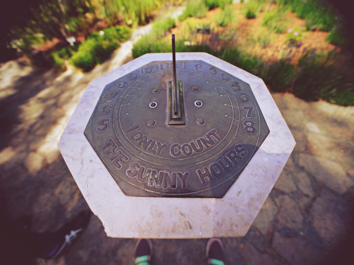 Wide angle view of a sundial at the Berkeley Botanical Garden that is labeled, "I only count the sunny hours"