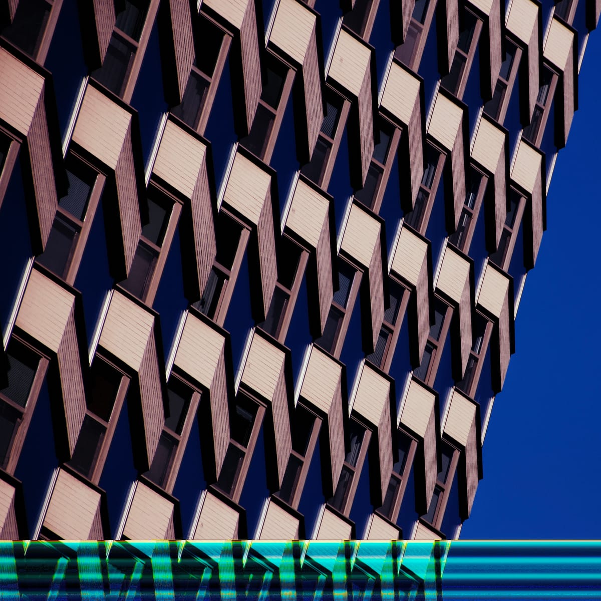 Abstract picture of the windows of a building against a blue sky, with a band of a digital glitch at the bottom edge