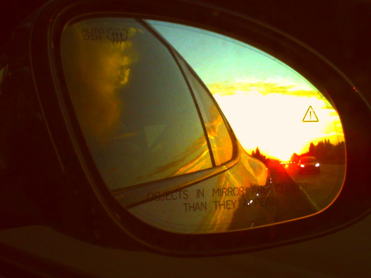 Overexposed picture of a sunset framed in a car's passenger-side mirror