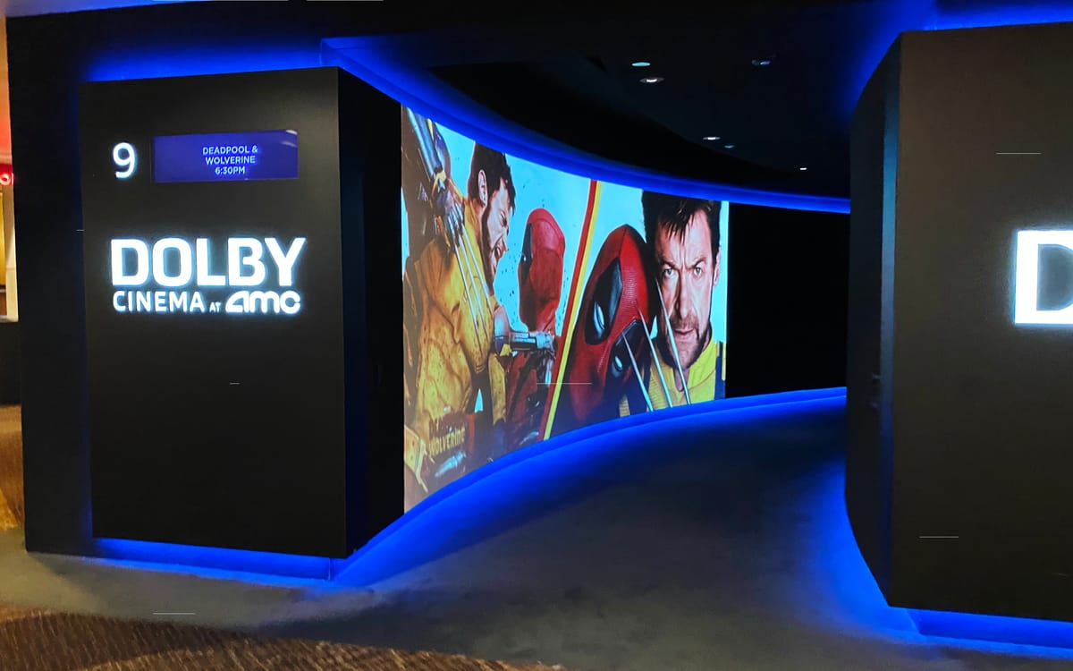 Entrance to a movie theatre showing Deadpool and Wolverine which has a video screen showing the two characters' movie art