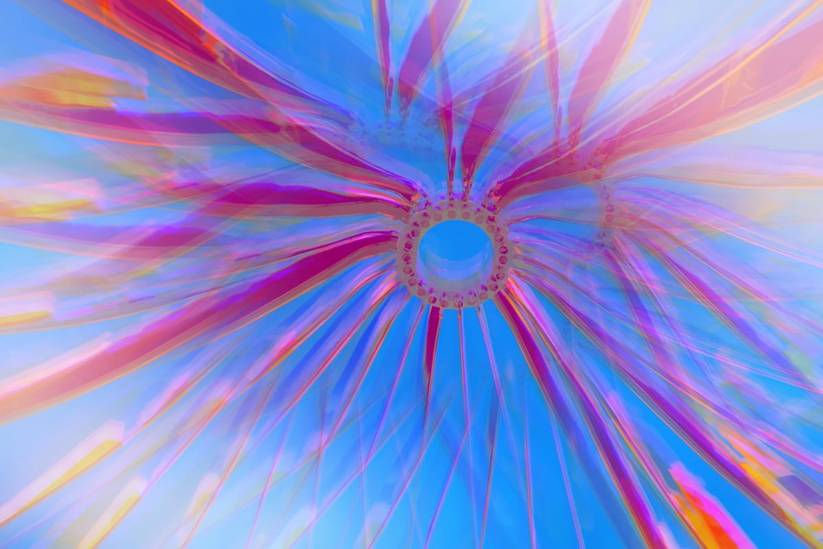 Abstract image of a circular shape with several curvy, swooping arms radiating from it, surreal vivid colors