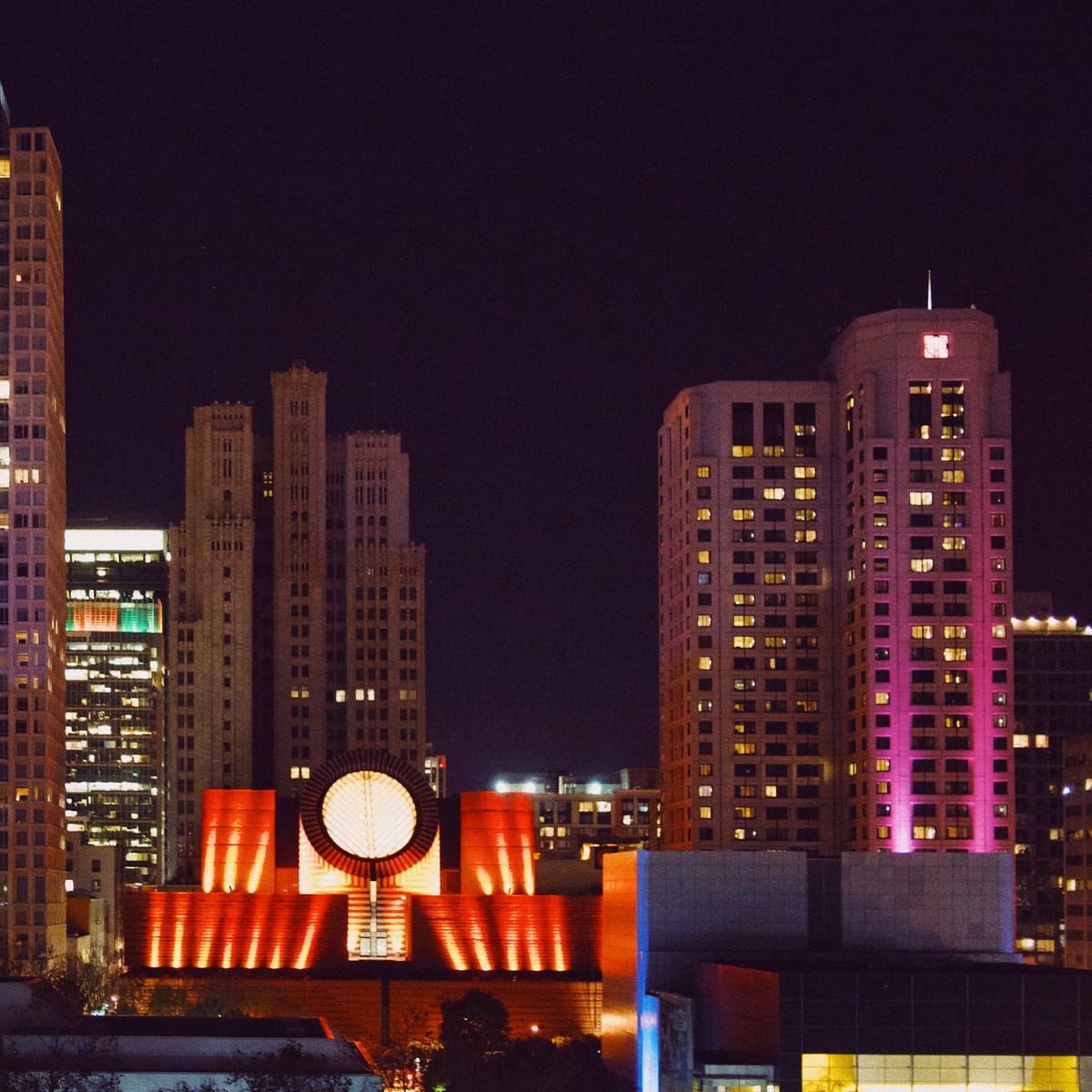 Cropped in view of downtown SF overlooking SFMOMA and surroundings at night, buildings lit with vivid colors