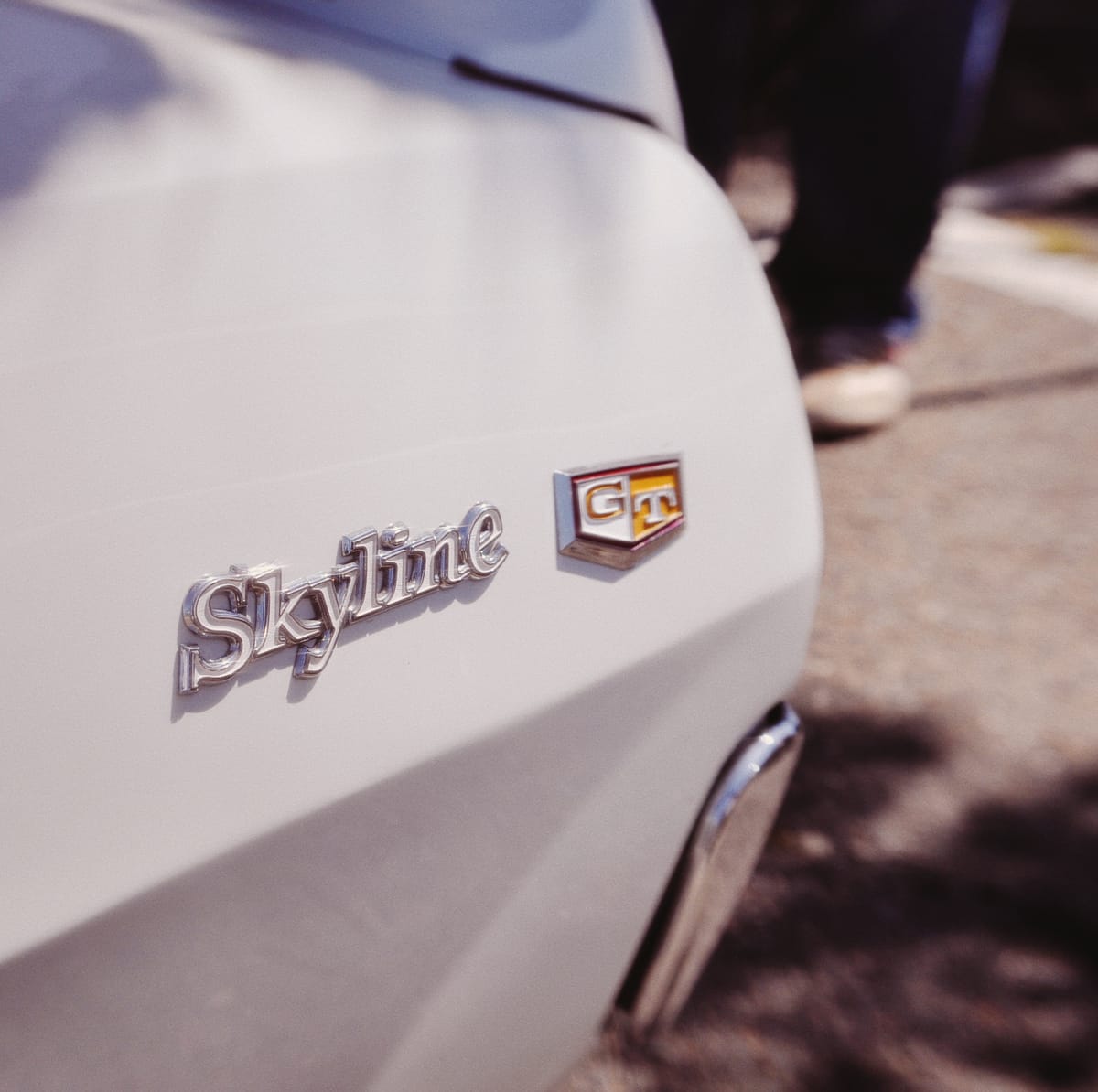 Close-up of a vintage white Nissan Skyline GT's badge with slight distortion around picture edge from the Lensbaby lens