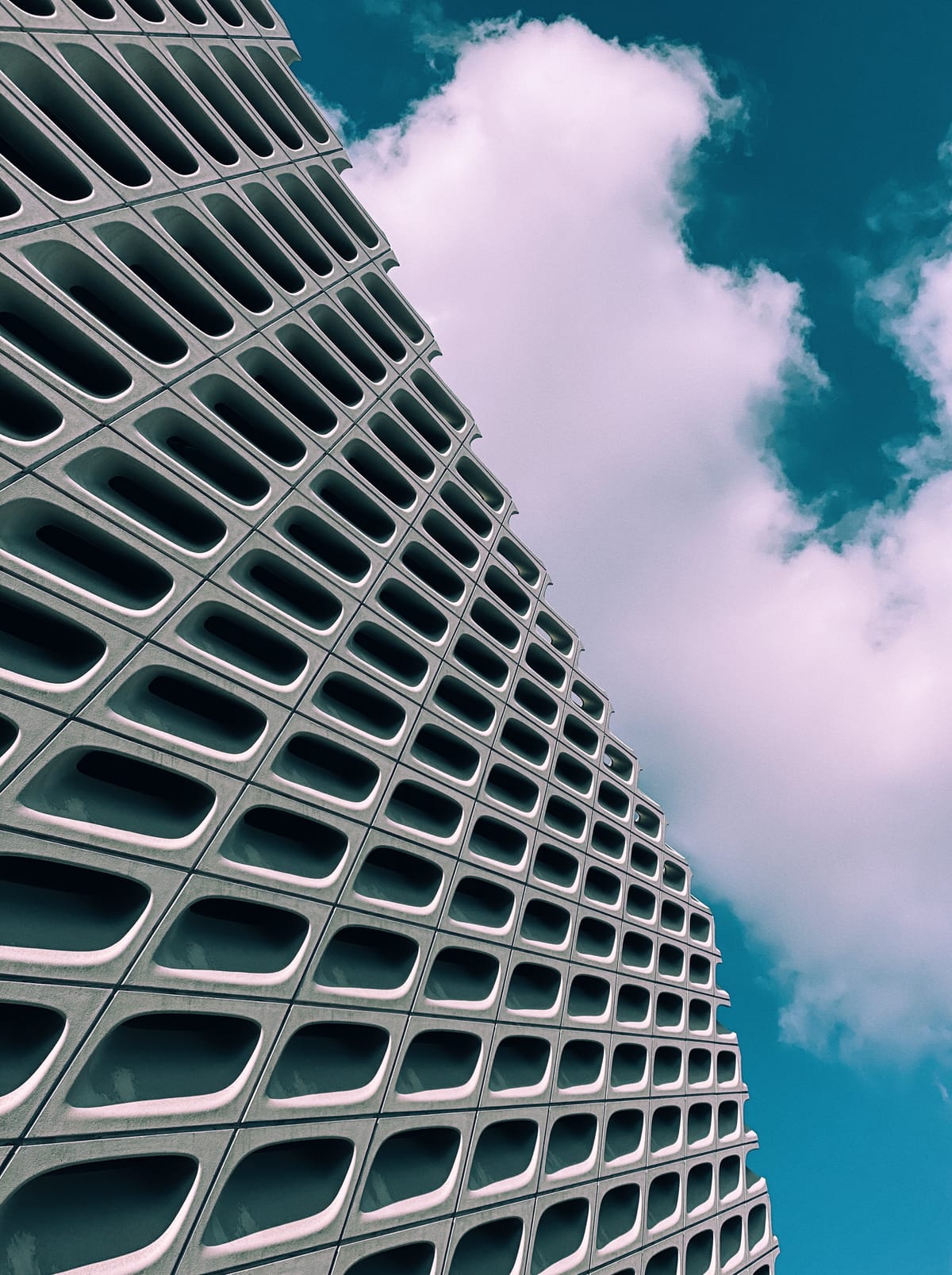 Looking up at the curvy grid side of The Broad against a partly cloudy blue sky