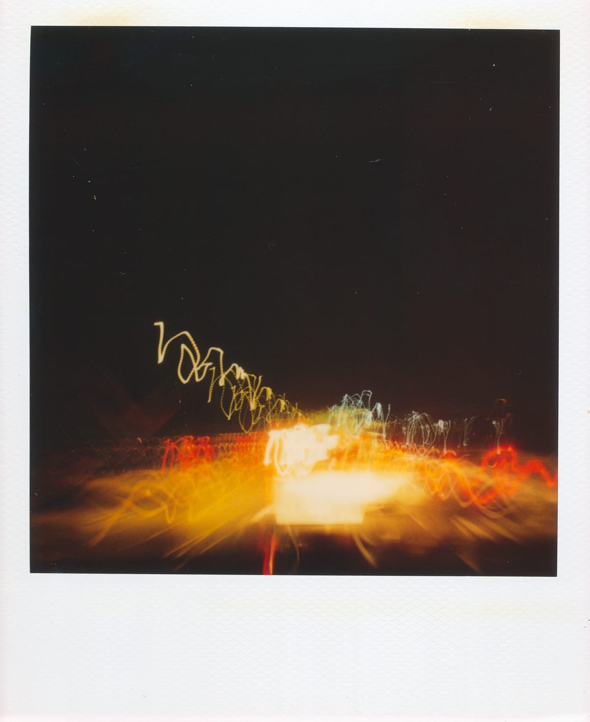 Polaroid picture of a long shutter speed capture of traffic on the highway, an abstract jumble of light trails at night