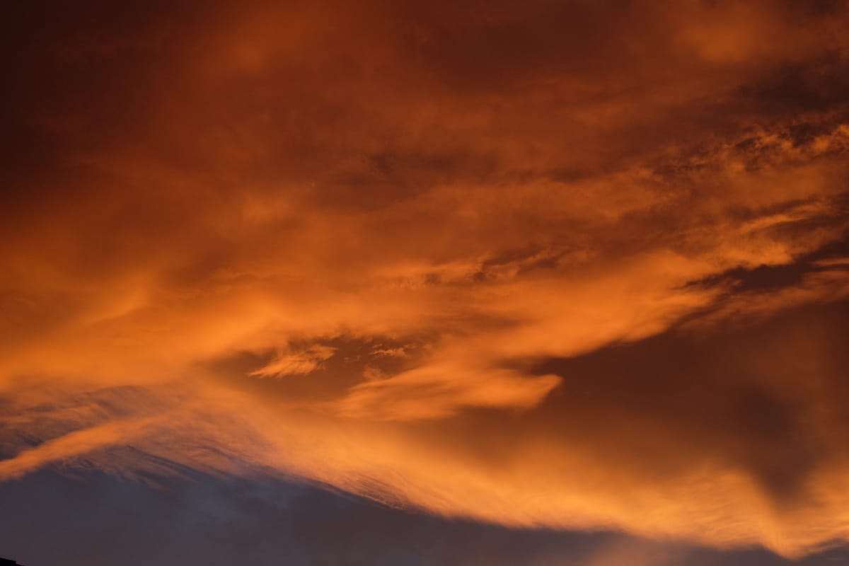 Vibrant picture of a blanket of deep orange-red clouds at sunset with a dark blue sky peeking in from the bottom