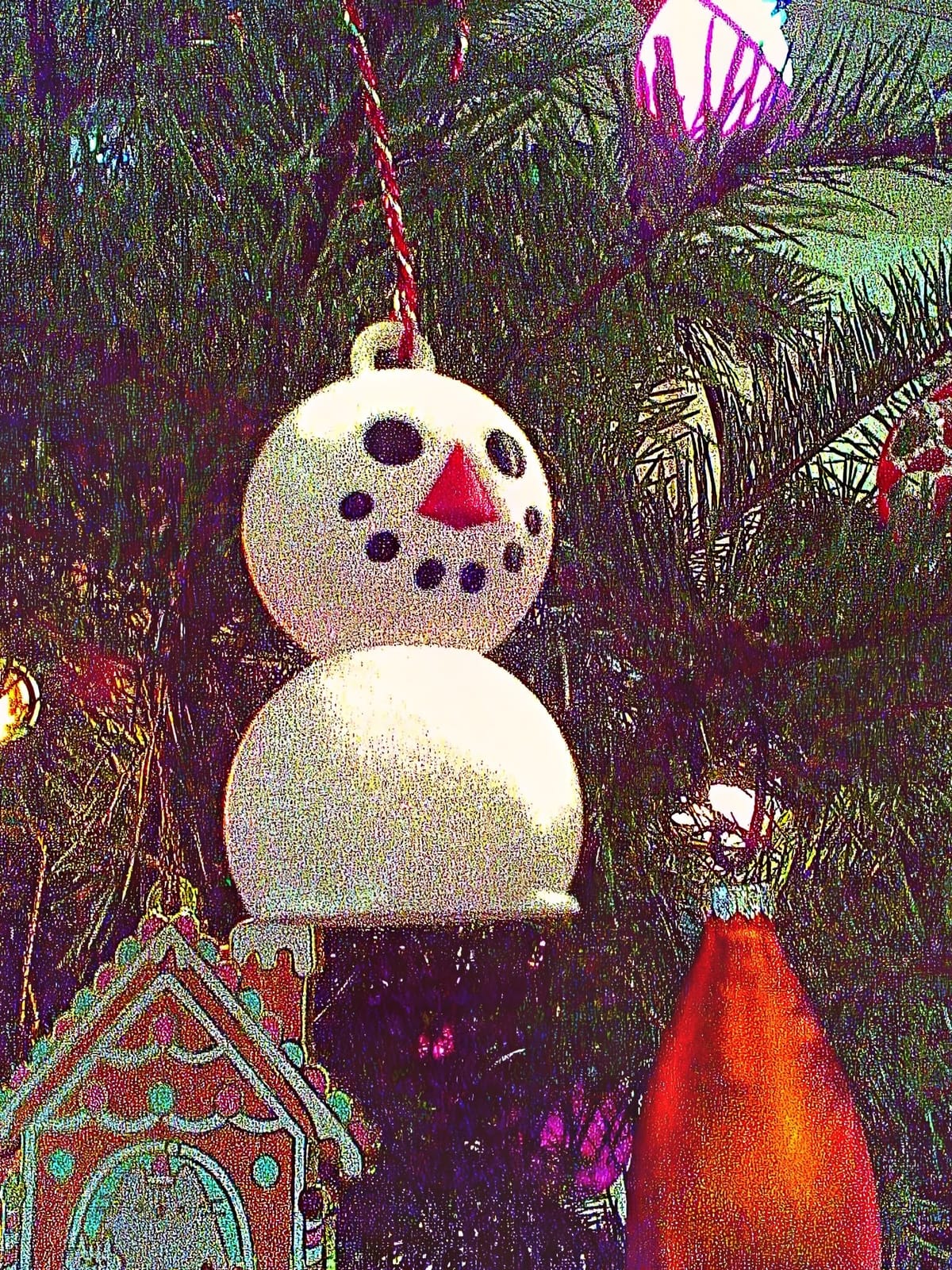 Noisy, low-res picture of a 3D-printed Snowboy ornament hanging on a Xmas tree among other ornaments and lights