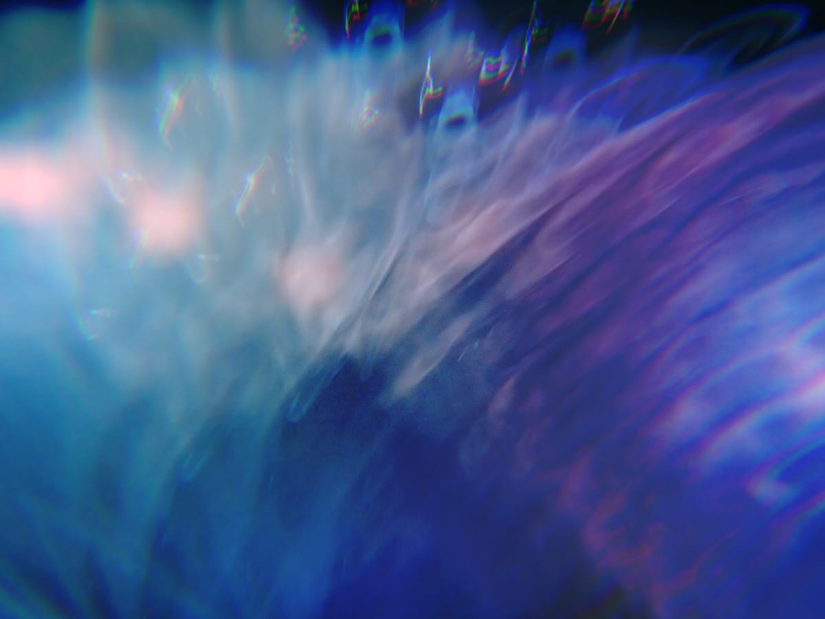 Abstract close-up image of a water vortex in shades of blue, aqua, pink, and purple with dynamic lighting